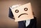 Businessman gesturing with cardboard box on his head with sad fa