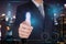 Businessman give a thumbs up for compliment as praise, scanning finger security futuristic hi-tech on blur night cityscape