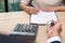 Businessman giving key and customer signing loan agreement document with calculator on wooden desk.