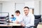 Businessman with glasses smiling at his desk in office on the ba