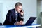 Businessman gray in a suit talking on the phone in front of laptop.