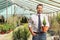 Businessman in a greenhouse holding a small evergreen tree in a pot