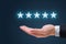 Businessman hand holding five stars isolated on blue background