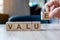 Businessman hand holding wooden cube block with Value business word on table background. Mission, Vision and core values concept