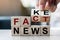 Businessman hand holding wooden cube with flip block FAKE to FACT News word on table background. News, solution and business