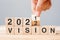 Businessman hand holding wooden cube and flip over block 2021 to 2022 VISION on table background. Resolution, plan, goal, mission