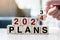 Businessman hand holding wooden cube with flip over block 2023 to 2024 Plans word on table background. Resolution, strategy,