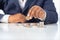 Businessman hand with putting money coins a desk in the office.concept: Saving money wealth and financial Personal, finance