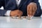 Businessman hand with putting money coins a desk in the office.concept: Saving money wealth and financial Personal, finance