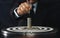 Businessman hands in black suite sitting and holding black dart put to centre of target board with stacking coin on vintage table