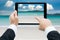 Businessman hands tablet taking pictures beach and sea