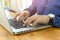 Businessman hands typing on a laptop computer on wooden desk in office.