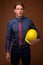 Businessman with hardhat against brown background