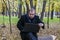 Businessman having a laptop in the park in the fall. Young man sitting on tree in park with laptop on his lap and checks e-mail.