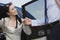 Businessman Helping Businesswoman To Get Down By Car