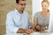 Businessman and hispanic business woman working with computer in sunny office. Group of diverse people