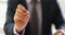 Businessman holding ballpoint pen in front of camera at work in office closeup