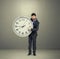 Businessman holding big white clock