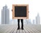 businessman holding black blank chalkboard with skyscraper cityscape