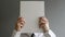 Businessman holding blank paper in front of his face with copy space
