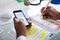 Businessman Holding Cellphone Writing Schedule In Diary