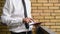 Businessman holding digital tablet computer, standing at the office balcony with yellow brick wall