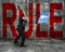 businessman holding hammer hitting red RULE word on concrete wall