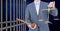 Businessman holding judge gavel and scales by prison cell