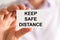 Businessman holding Keep Safe Distance message card