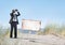 Businessman Holding Megatelescope with Empty Signboard on Beach