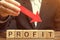 A businessman is holding a red down arrow over wooden blocks with the word Profit. Unsuccessful business. Loss of investment. Low
