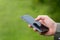 Businessman holding a smart phone, on a green summer day.