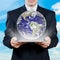 businessman holding tablet displaying earth with sky in background, business globalization concept