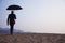 Businessman holding an umbrella and walking away in the middle of the desert