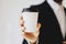 Businessman holding white paper coffee cup to take away.Mock up of clean carton coffee cup.Horizontal mockup, blurred
