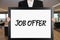 Businessman holds a big signboard with the message job offer. Job recruitment announcement