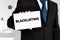 Businessman holds a card with the word blacklisting written on it. s
