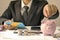 Businessman holds a coin on a piggy bank and is examining a business investment.