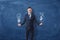 Businessman holds a lightbulb in one hand and a bag of money in another hand on blue chalkboard background