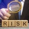 Businessman holds a magnifying glass over the word Risk. Financial and commercial risk concept. Risks assessment and management.