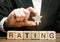 Businessman holds one star above the wooden blocks with the word Rating. Concept of negative feedback. Low quality and service