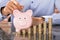 Businessman Insert Coins In Piggy Bank