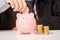 Businessman insert gold coin into piggy bank