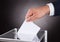 Businessman inserting ballot in box on desk