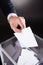 Businessman inserting ballot in box on desk