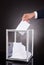 Businessman inserting ballot in box on desk