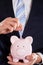 Businessman inserting coin in piggybank