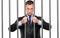A businessman in jail holding bars