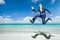 Businessman jumps in black suit on tropical beach.