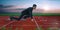 Businessman kneeling on the starting grid of a running track